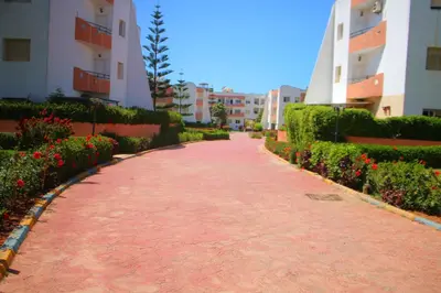 a red brick walkway between two buildings with flowers at Mohammedia Appartement in Mohammedia