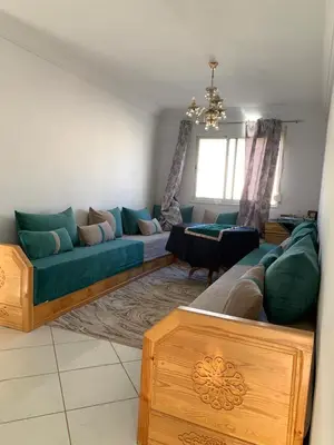 a living room with a blue couch and a table at Résidence MaRwa in Oulad Kerroum