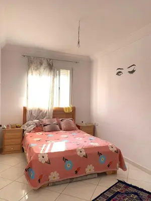 a bedroom with a bed with a orange comforter at Résidence MaRwa in Oulad Kerroum