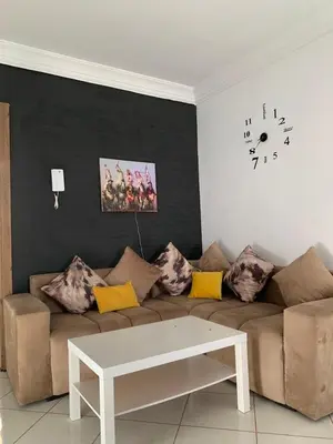 a living room with a couch and a clock on the wall at Résidence MaRwa in Oulad Kerroum