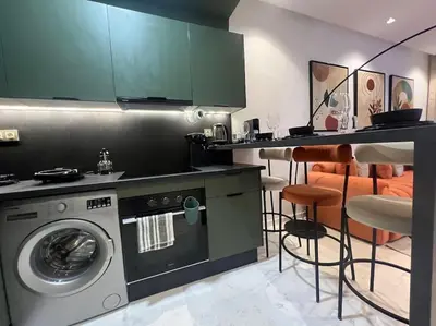 a kitchen with a washing machine and a counter with chairs at Luxury Residence So Stylish & Bright Appartement Hotel Au Coeur de Casablanca prés de Carrefour et 3 Min de La Gare Ferroviere Oasis in Casablanca