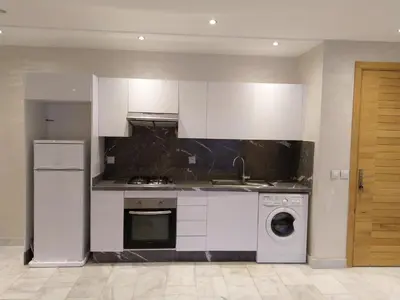 a kitchen with white cabinets and a washer at Sweet Home in Maarif
