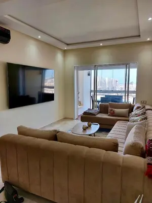 a living room with a large couch and a tv at Cosy Apartment with sea view in Sidi Rahal