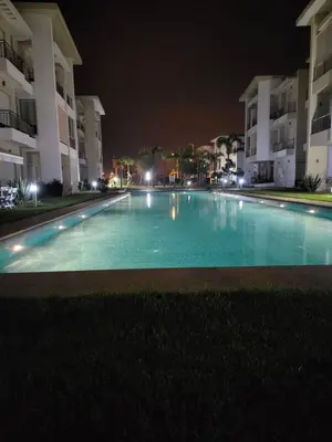 an empty swimming pool at night with buildings at Cosy Apartment with sea view in Sidi Rahal