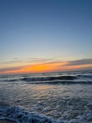 a beach with waves and a sunset in the ocean at Cosy Apartment with sea view in Sidi Rahal