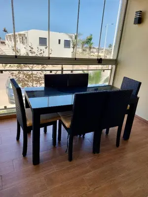 a dining table and chairs in a room with a large window at Cosy Apartment with sea view in Sidi Rahal
