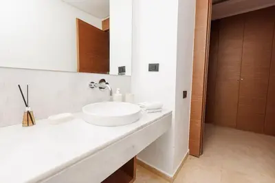 a white bathroom with a sink and a mirror at Luxury 2BR Apartment in Agdal for a Relaxing Stay in Es Souissi