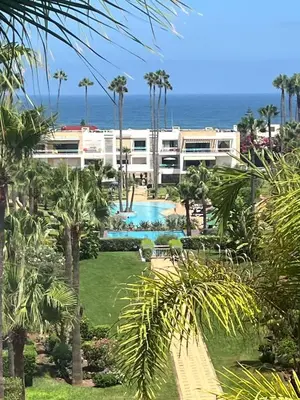 a resort with a pool and the ocean in the background at Eden in Dar Bouazza