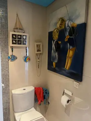 a bathroom with a toilet and a painting on the wall at Eden in Dar Bouazza