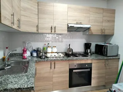 a kitchen with wooden cabinets and a sink and a microwave at Résidence les deux palmiers Temara Rabat in Temara