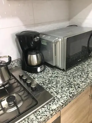 a microwave sitting on a counter next to a stove at Résidence les deux palmiers Temara Rabat in Temara