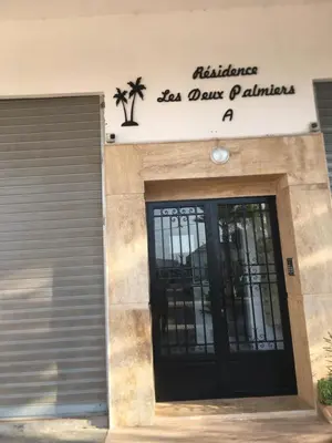 a building with a black door with a sign above it at Résidence les deux palmiers Temara Rabat in Temara