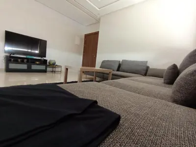 a living room with a couch and a flat screen tv at Magnifique appart vue piscine 5min de la plage in Kasba Bou Hamira