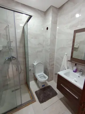 a bathroom with a shower and a toilet and a sink at Magnifique appart vue piscine 5min de la plage in Kasba Bou Hamira