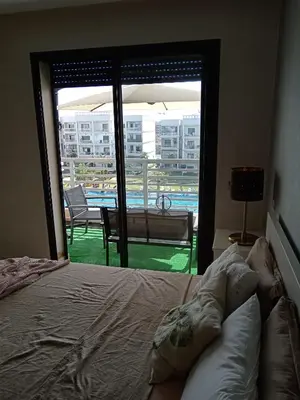 a bedroom with a bed and a view of a balcony at Magnifique appart vue piscine 5min de la plage in Kasba Bou Hamira
