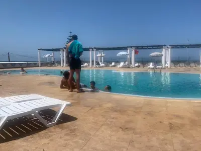 a man standing next to a swimming pool at Beach apartment in Dar Bouazza