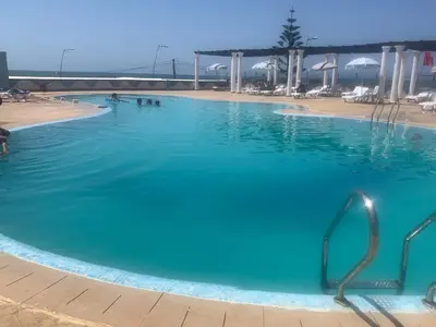 a large swimming pool with blue water at Beach apartment in Dar Bouazza