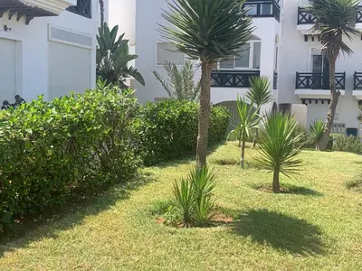 a yard with palm trees in front of a building at Beach apartment in Dar Bouazza