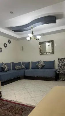a living room with a blue couch and a mirror at Appart meublé 5min de la plage à Bouznika in Bouznika