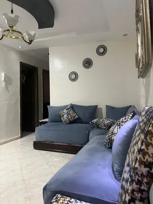 a blue couch in a living room with clocks on the wall at Appart meublé 5min de la plage à Bouznika in Bouznika