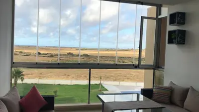 a living room with a large window looking out at a field at Evasion bouznika in Sidi el Haj Bou Derbala