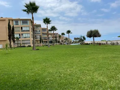 a park with palm trees and a building at Evasion bouznika in Sidi el Haj Bou Derbala