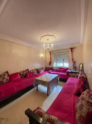 a living room with red couches and a table at Appartement Neo in Oulad Hamida