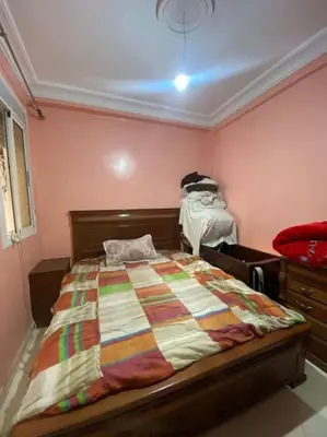a bedroom with a bed in a room with pink walls at Appartement Neo in Oulad Hamida