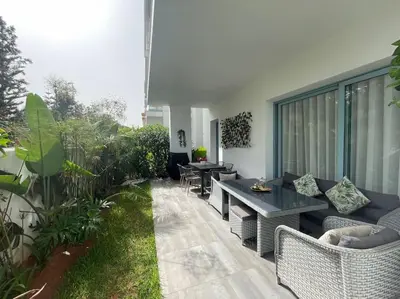a patio with a table and some chairs and a table at Eden Island Bouznika Bel appartement avec jardin in Bouznika