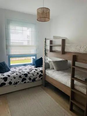 a bedroom with two bunk beds and a window at Eden Island Bouznika Bel appartement avec jardin in Bouznika