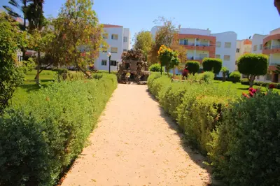 a dirt path in a park with bushes and buildings at Mohammedia 2 in Mohammedia
