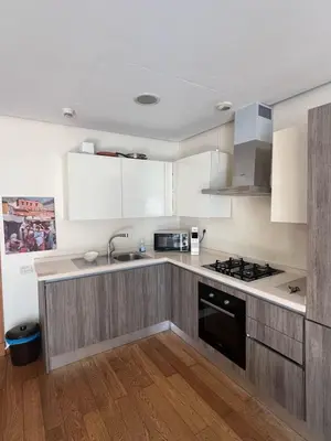 a kitchen with white cabinets and a sink and a stove at Luxueux Studio à La marina in LʼOasis