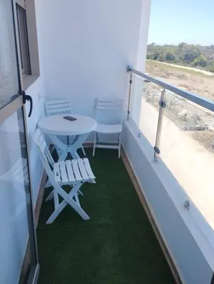 a room with a table and chairs on a balcony at appartement jinane in Bouznika