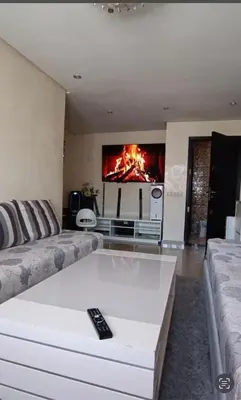 a living room with a couch and a fire in the fireplace at الشقة دار بوعزة in Dar Bouazza