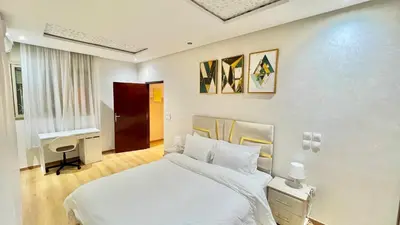 a bedroom with a white bed and a desk at T1 App moderne 2 chambres, a 10 min du Stade Moulay Abdellah in Temara