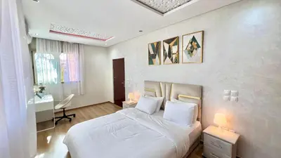 a bedroom with a white bed and a desk at T1 App moderne 2 chambres, a 10 min du Stade Moulay Abdellah in Temara