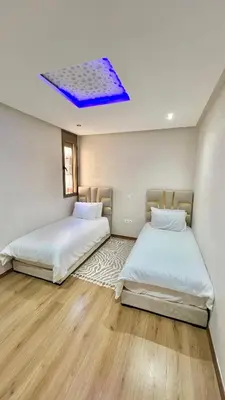 two beds in a room with a blue ceiling at T1 App moderne 2 chambres, a 10 min du Stade Moulay Abdellah in Temara