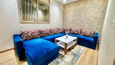 a blue couch in a living room with a table at T1 App moderne 2 chambres, a 10 min du Stade Moulay Abdellah in Temara