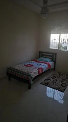 a bedroom with a bed and a rug on the floor at Bel appartement à bouznika in Bouznika