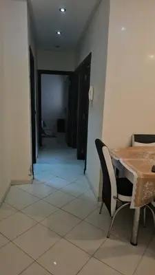 a dining room with a table and chairs and a hallway at Bel appartement à bouznika in Bouznika