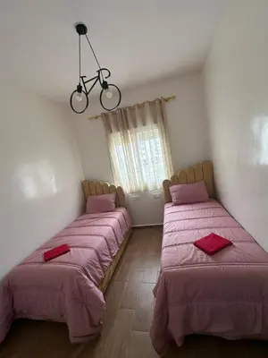 a bedroom with two beds with pink sheets and a bike on the ceiling at Appartement Casablanca proche de la mer in Dar Mouddene