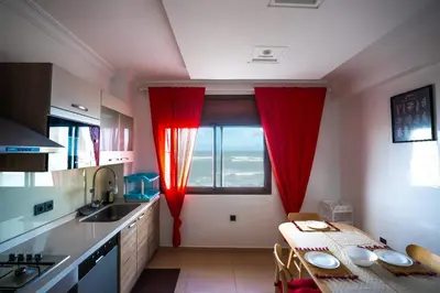 a kitchen with red curtains and a table in front of a window at Spacious Beachfront apartment in Casablanca