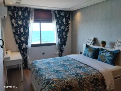a bedroom with a bed and a window with the ocean at Spacious Beachfront apartment in Casablanca