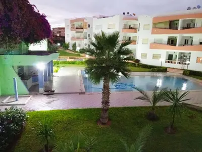 an apartment complex with a palm tree and a swimming pool at superbe appartement Al Mansouria-les jardins de l'Atlantique in Pont Blondin