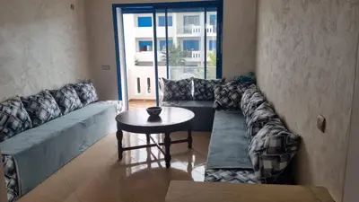 a living room with a couch and a table at Très bel Appartement avec Piscine et Jardin in Mansouria