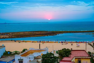 a group of people on a beach at sunset at Beautiful and Stylish 2BR Appartment with a wide Beach View in Mohammedia