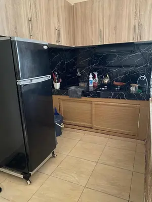 a kitchen with a black refrigerator and wooden cabinets at Magnifique Studio Gare - Tram in Les Camps