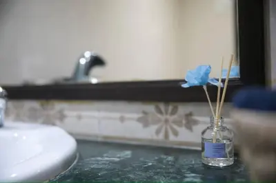 a glass vase with a blue flower in a bathroom at Appartement moderne en plein centre de l'Agdal in Rabat