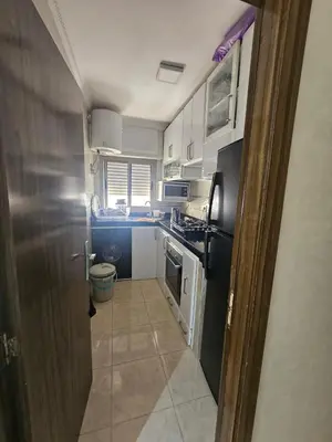 a kitchen with white cabinets and a black appliances at Appartement proche de la mer de bouznika in Bouznika