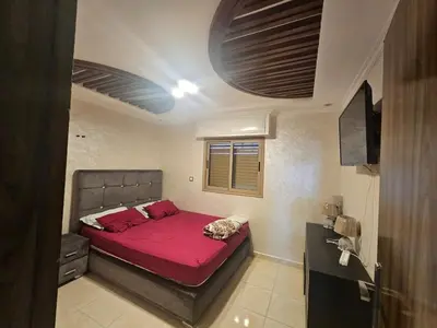 a bedroom with a large bed with red sheets at Appartement proche de la mer de bouznika in Bouznika